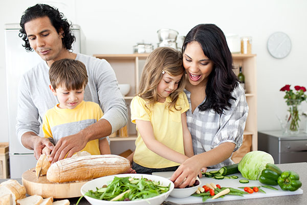 A mom and dad with two kids making a salad together