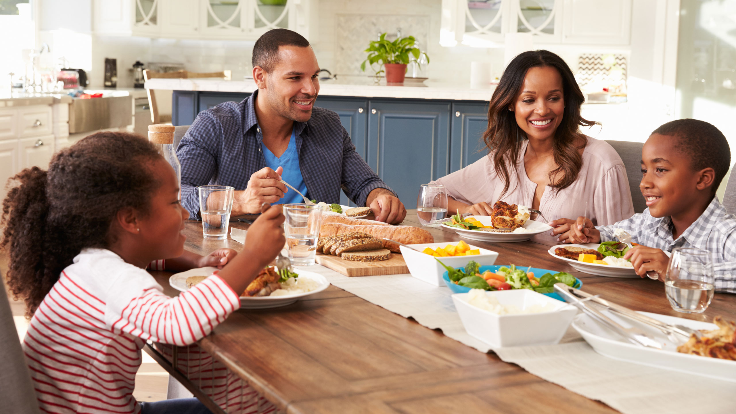 a family of four (two adults and two children) eating at the dinner table